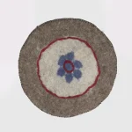 Detail of hand-felted blue flower on natural sheep wool
