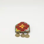 Close-up of handmade Turkmen embroidered brooch with vibrant silk needlework on emerald green fabric and three bronze pendants