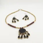 Close-up of handmade Turkmen tribal earrings with black teardrops