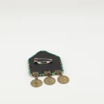 Detail shot of traditional Turkmen süzme needlework brooch in emerald green with antique bronze pendants