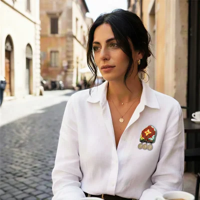 Woman wearing handmade Turkmen silk embroidery brooch with small dangling bronze medals on coat