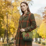 A girl hanging a Handmade felt crossbody bag in green with red poppy wool painting by Iranian Turkmen artisan, zipper open showing blue lining