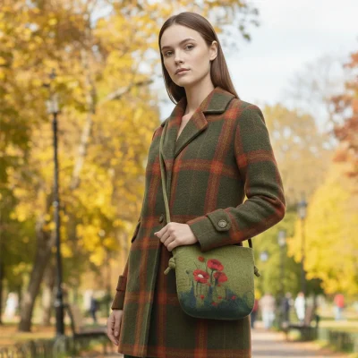 A girl hanging a Handmade felt crossbody bag in green with red poppy wool painting by Iranian Turkmen artisan, zipper open showing blue lining